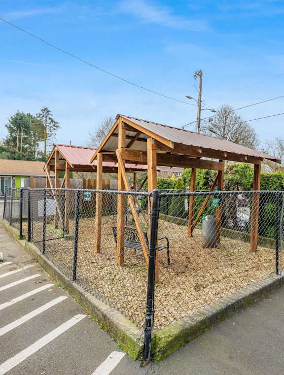 A playground with a wooden structure and a black fence.