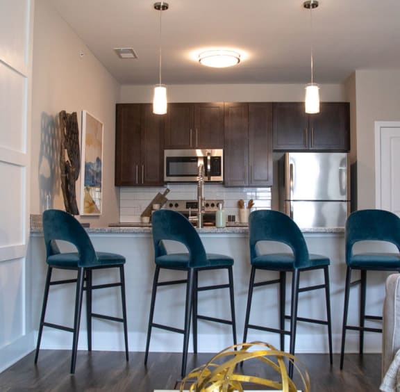 a kitchen with a counter top that has three stools in front of it at The Century at Purdue Research Park-Student, West Lafayette, 47906