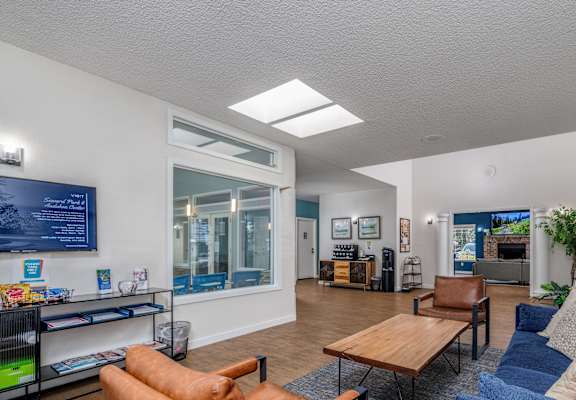 A living room with a blue couch and a brown leather chair.