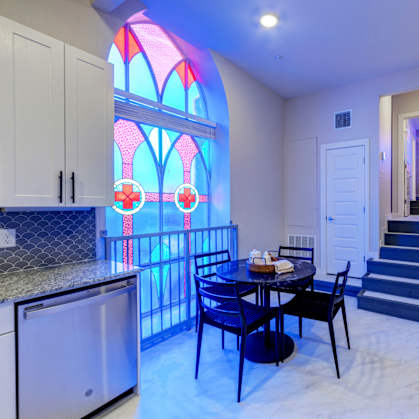A kitchen with a table and chairs and a stained glass window.