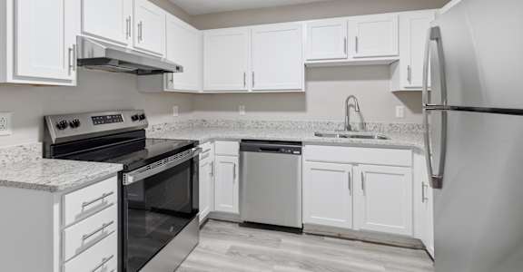 A kitchen with white cabinets and appliances.