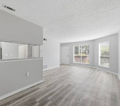 A spacious room with wooden flooring and white walls.