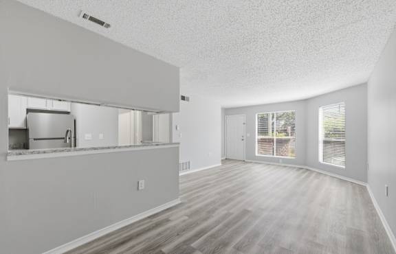 A spacious room with wooden flooring and white walls.