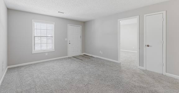 A room with a carpeted floor and two doors.