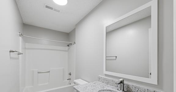 A white bathroom with a toilet, sink, and mirror.