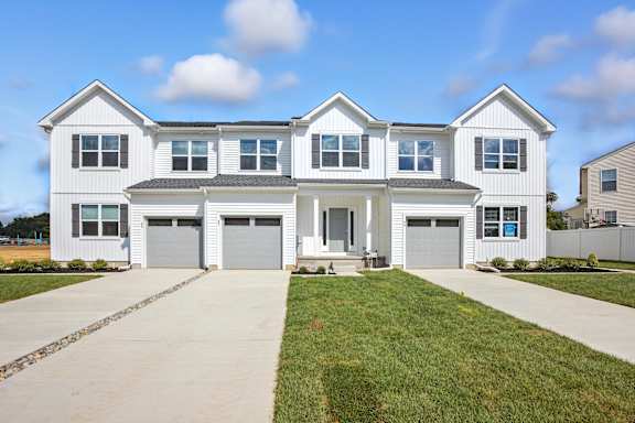 A large white house with a grey roof and a grey garage door.