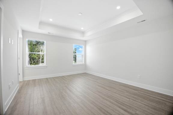 A spacious room with light wood flooring and white walls.