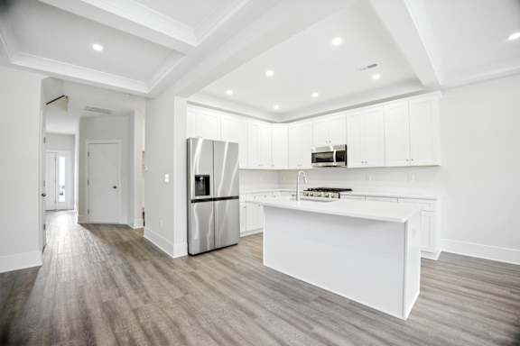 A modern kitchen with white cabinets and a wooden floor.