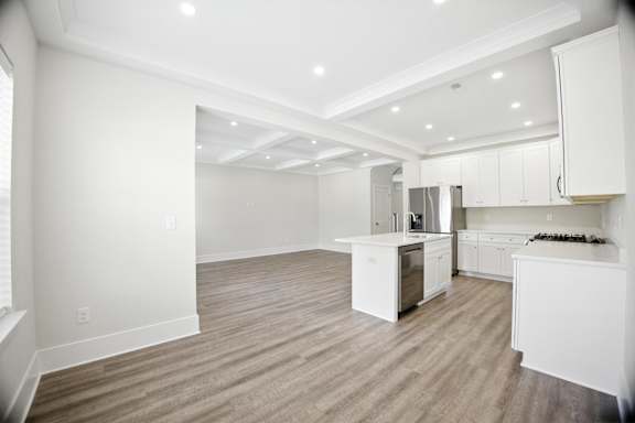 A spacious kitchen with white cabinets and a wooden floor.