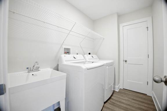 A white bathroom with a sink and a washer and dryer.