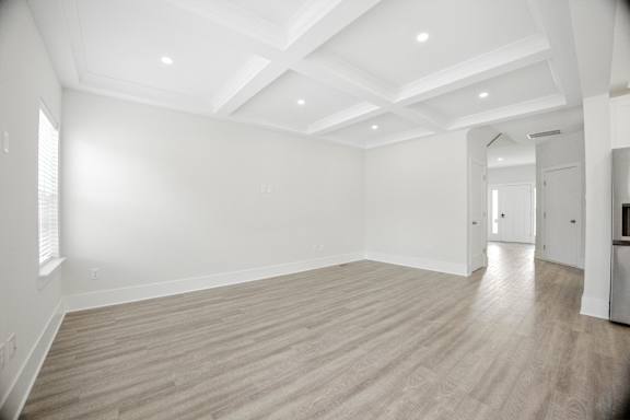 A spacious room with wooden flooring and white walls.