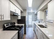 Thumbnail 5 of 5 - A kitchen with black appliances and white cabinets.