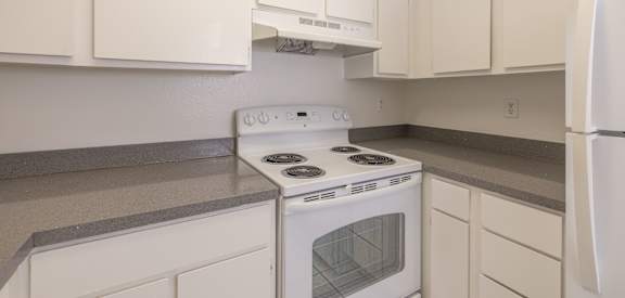 A white stove and oven in a kitchen with white cabinets.