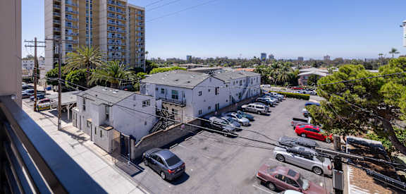 A parking lot with cars and a building with a flag on top.