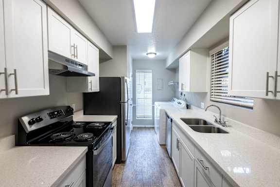 A kitchen with black appliances and white cabinets.