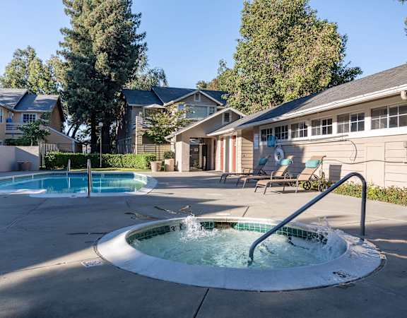 a hot tub in the middle of a pool in front of a house