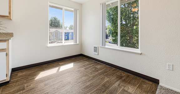 A room with a ceiling fan and two windows.