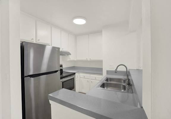 A modern kitchen with a stainless steel refrigerator and a sink with a faucet.