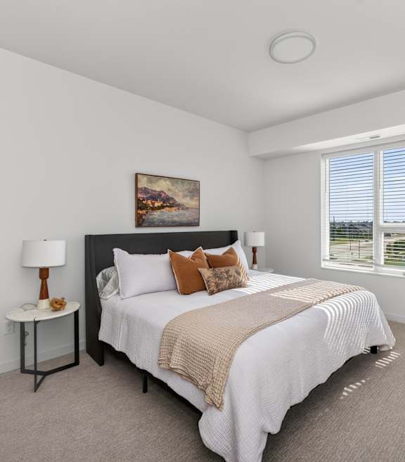 A bedroom with a large bed and a painting on the wall.