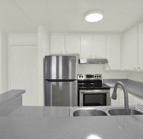 A modern kitchen with a stainless steel refrigerator and a sink.