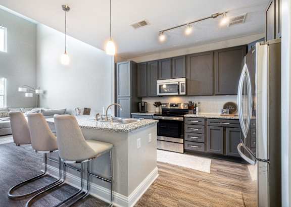 a kitchen with black cabinets and a granite counter top at Streets of Greenbrier in Chesapeake, VA 23320