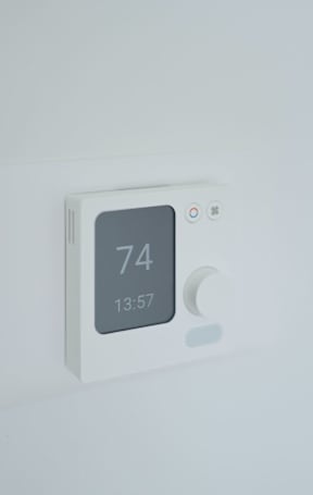 A white thermostat shows the temperature as 74 degrees and the time as 13:57.