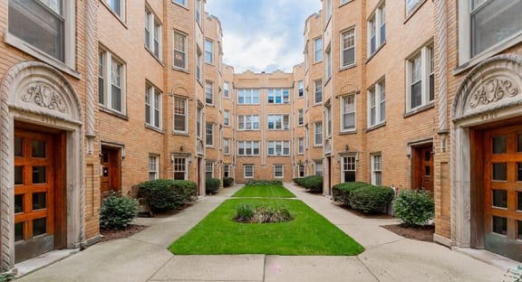 the courtyard of an apartment building with a green lawn in the middle