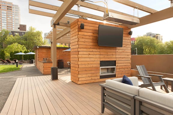 A living room with a grey couch and a wooden entertainment unit.