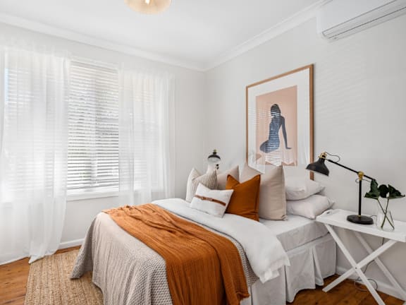 A bedroom with a bed, a nightstand, and a painting on the wall.