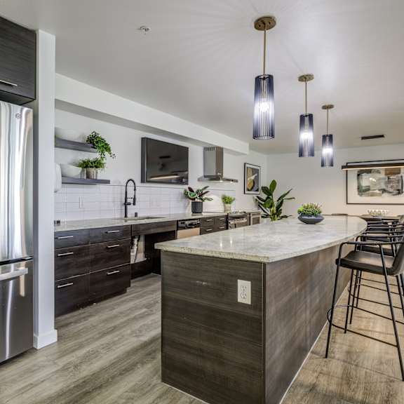 a kitchen with a large island and stainless steel refrigerator