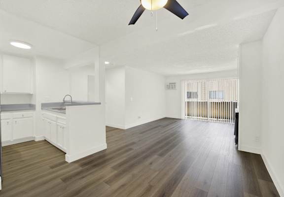 A spacious kitchen with white cabinets and a wooden floor.
