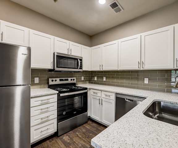 a kitchen with white cabinets and stainless steel appliances at Ventana Oaks Apartments, Texas