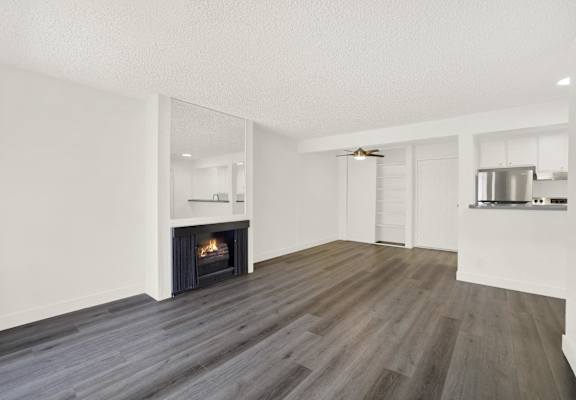 an empty living room with a fireplace and a kitchen