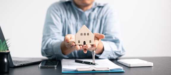 A person is holding a small model house in their hands.