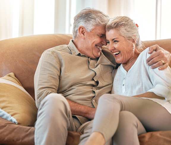 a man and a woman sitting on a couch laughing