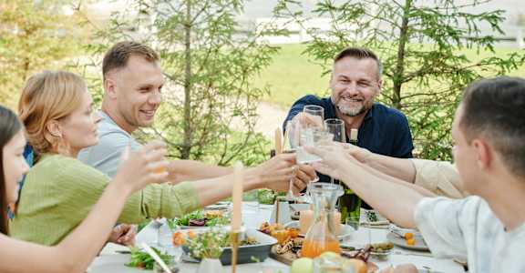 A group of people toasting with drinks at a dinner table.