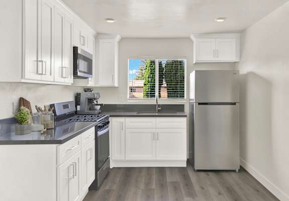 A modern kitchen with white cabinets and a stainless steel refrigerator.