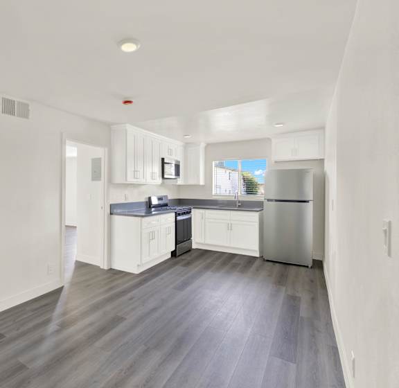 A modern kitchen with white cabinets and a grey floor.