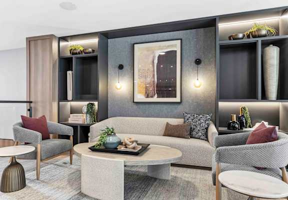A modern living room with a grey sofa, a grey armchair, a white coffee table, and a grey rug.