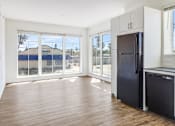 Thumbnail 5 of 7 - A black refrigerator sits in a kitchen with wood floors and white walls.
