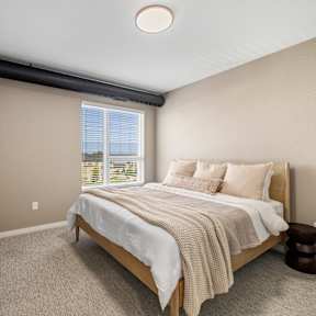 A bedroom with a large bed and a window overlooking the ocean.