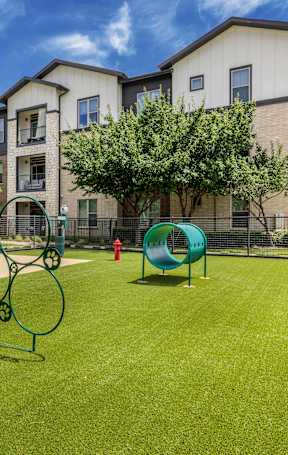 A playground with a slide, swings, and a bench in front of a building.