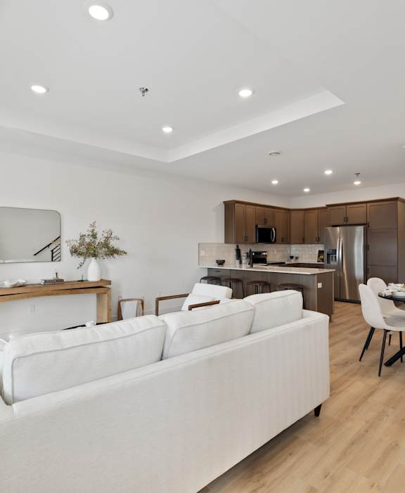 A white couch sits in a modern living room with a dining table and chairs.