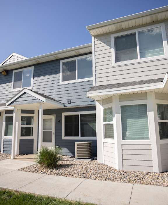 A row of houses with grey siding and white trim.