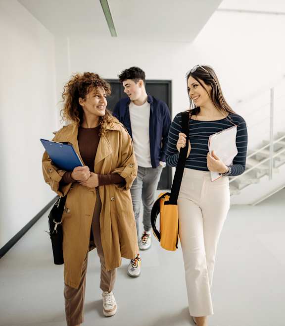 Three people walking in a hallway, one holding a clipboard.