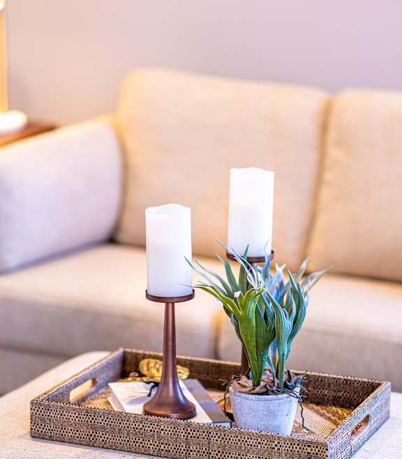 A table with a candle holder and a plant on it.