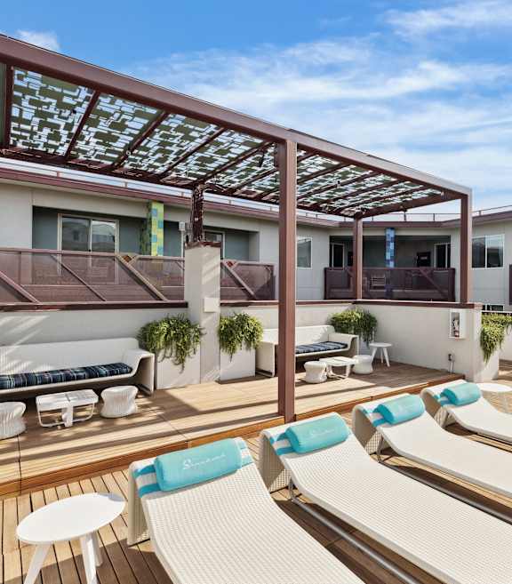 A sunny day at the rooftop patio with white lounge chairs and blue cushions.