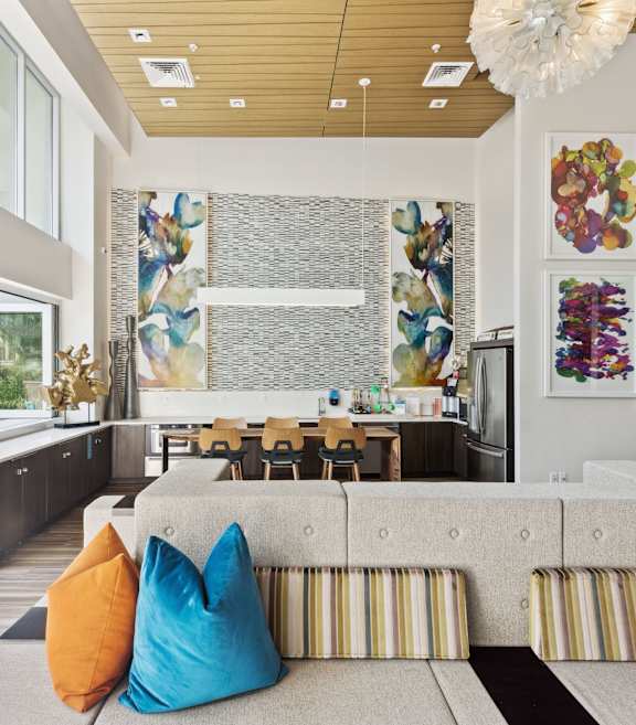 A living room with a blue couch and a large painting on the wall.