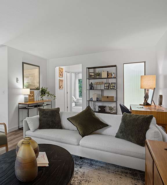 A living room with a white couch and a wooden coffee table.
