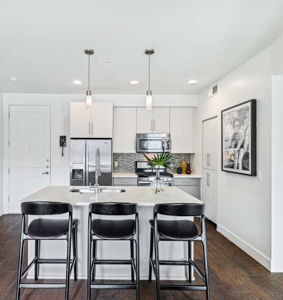 A kitchen with a white table and black chairs.